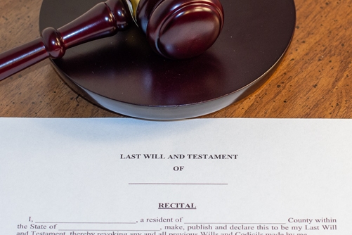 A Michigan Last Will and Testament laying on a desk with a judges gavel above it symbolizing estate litigation for wills